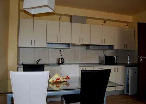 シャールヴァールにあるÁdám Apartmanの白いキャビネット、テーブルと椅子付きのキッチンが備わります。