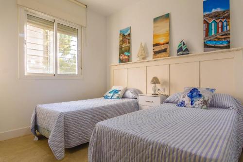 a bedroom with two beds and a window at Chalet individual en el Rompido urb Urverosa in El Rompido