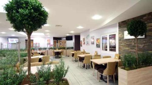 a restaurant with tables and chairs and a tree at Oakdene Forest Park Violet 1 in Saint Leonards