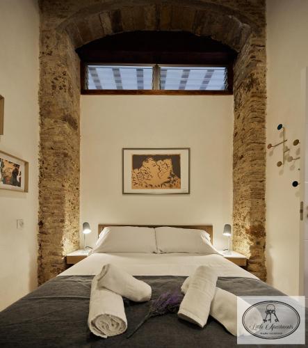 a bedroom with a large bed with brick walls at La Linda Little Apartments in Cádiz