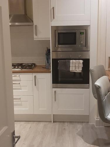 a kitchen with a stove and a microwave at Art Deco Property in Bromley in London