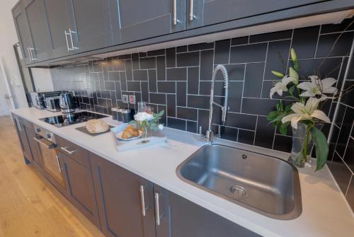 a kitchen with a stainless steel sink and blue tiles at 80 by Elite in Liverpool