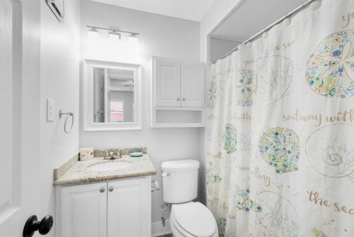 a bathroom with a toilet and a sink and a shower curtain at Villas on the Gulf unit C5 in Pensacola Beach
