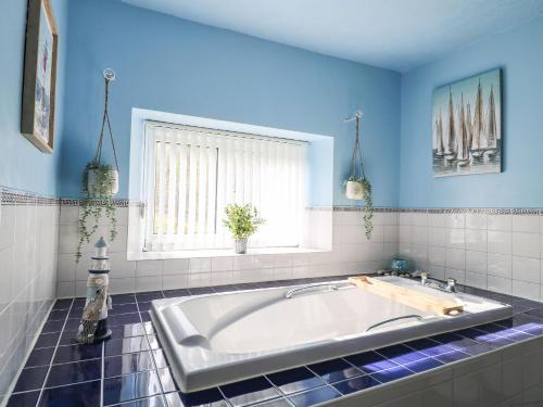 a large tub in a bathroom with blue walls and a window at The Old Post Office in Matlock