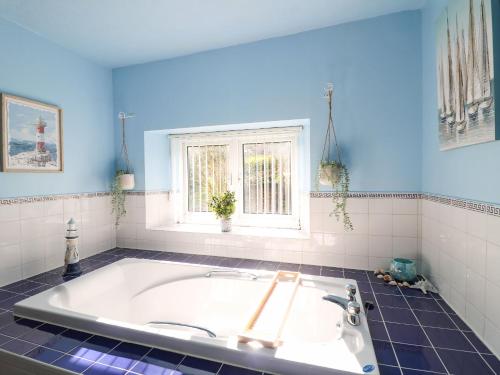 a bath tub in a bathroom with blue walls at The Old Post Office in Matlock