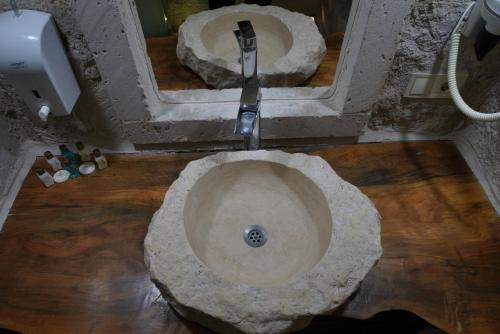 a bathroom with a stone sink and a mirror at Shoestring Cave House in Goreme
