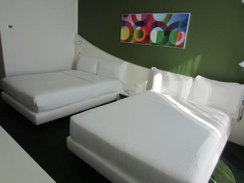 a room with two beds and a couch and a painting at Idea Hotel Milano Malpensa Airport in Case Nuove
