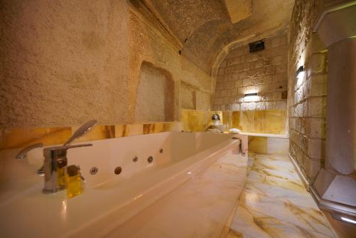 a large bathroom with a tub in a stone wall at Shoestring Cave House in Goreme