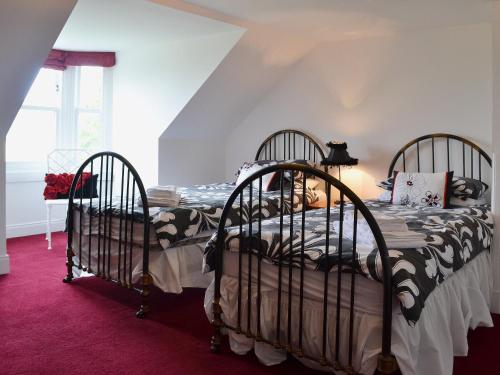 two twin beds in a bedroom with a red carpet at Kennels Cottage - Beaufort Estate in Belladrum