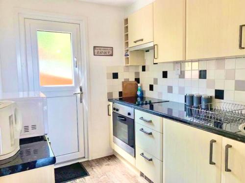 a kitchen with white cabinets and black counter tops at Chalet 95, Kingsdown Park in Deal
