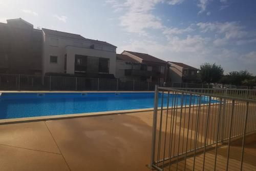 une clôture en face d'une piscine dans l'établissement Rêve de Bisca Appartement spacieux avec jardin privatif piscine et parking privés, à Biscarrosse
