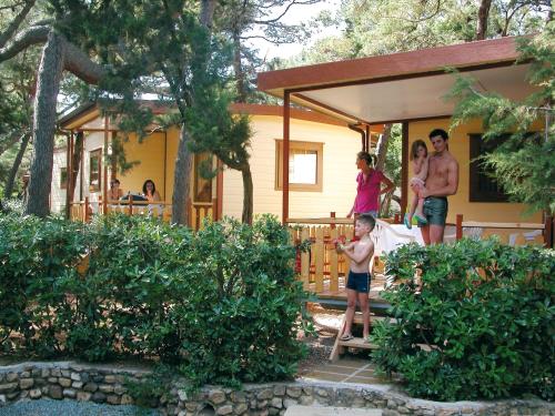 a group of people standing on the porch of a house at Le Esperidi Camping Ecoresort in Marina di Bibbona