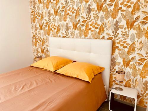 グロワにあるVilla Garance Ile et Villas Groixのベッドルーム1室(黄色い枕と壁紙のベッド1台付)