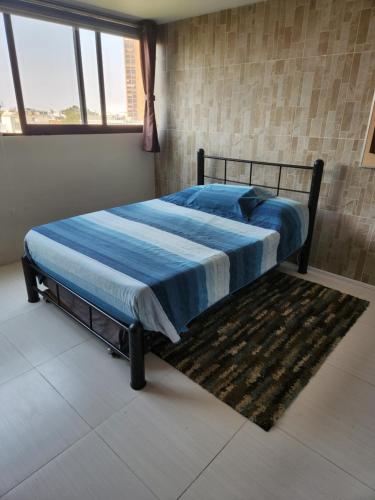 1 dormitorio con 1 cama con edredón azul y alfombra en Excelente ubicacion en colonia Del Valle en Ciudad de México
