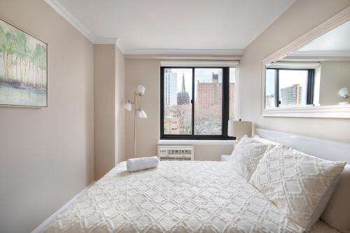 ein weißes Schlafzimmer mit einem Bett und einem Fenster in der Unterkunft LUXURY 4 BEDS 1.5 BATHS BY CENTRAL PARK in New York