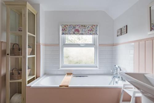 a bath tub in a bathroom with a window at Bunny Cottage by Bloom Stays in Hythe