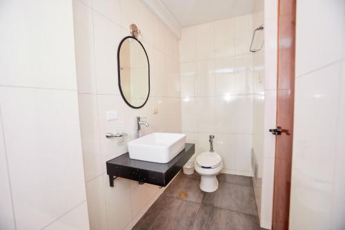 a white bathroom with a sink and a mirror at Samkauta Hotel & Suite in Juliaca