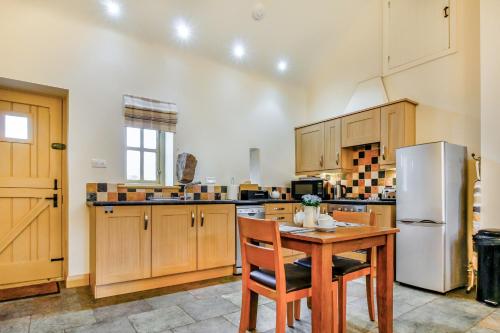 a kitchen with a wooden table and a refrigerator at No 3 The Dairy in Llangefni
