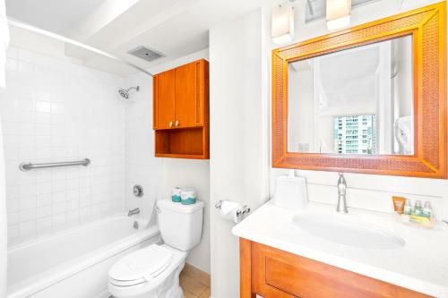 La salle de bains est pourvue d'un lavabo, de toilettes et d'un miroir. dans l'établissement Cozy Apt in Pacific Monarch - 1 Block to Beach!, à Honolulu