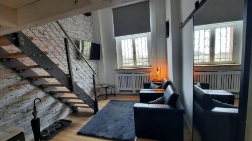 a living room with a staircase and couches and windows at Pension Zur Alten Post in Havelberg