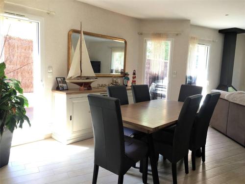une salle à manger avec une table en bois et des chaises noires dans l'établissement Maison spacieuse près de la mer à Saint-Brevin, 8 pers, jardin, WiFi, jeux, parking, bébé. - FR-1-392-126, à Saint-Brévin-les-Pins