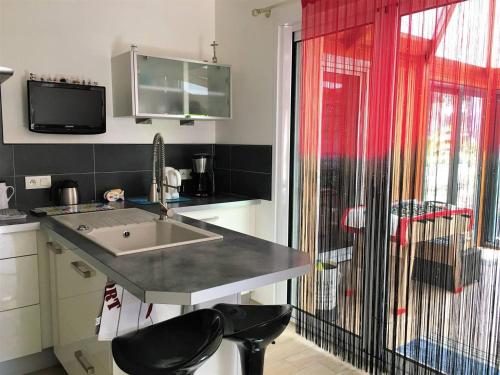 d'une cuisine avec évier, d'une télévision et d'une fenêtre. dans l'établissement Maison spacieuse près de la mer à Saint-Brevin, 8 pers, jardin, WiFi, jeux, parking, bébé. - FR-1-392-126, à Saint-Brévin-les-Pins