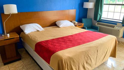 a bedroom with a large bed with a red blanket at Luxury Inn Forrest City in Forrest City