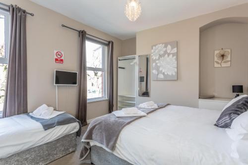 a bedroom with two beds and a tv and a window at The Avenue Belfast in Belfast