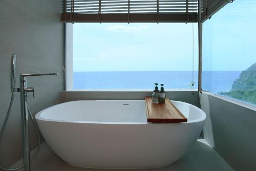 a white bath tub in a bathroom with a window at Royal Avila Boutique Resort in Senggigi 