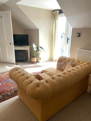 um sofá castanho numa sala de estar com lareira em The Old Workhouse Paddocks em Bawdeswell