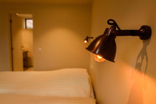 una lámpara colgada en una pared junto a una cama en 't Knus Gewilg, en Avelgem