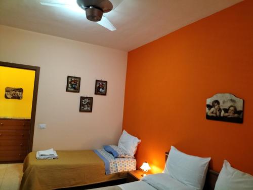 a bedroom with two beds and an orange wall at Casa Vacanza Da Rosa in Letojanni