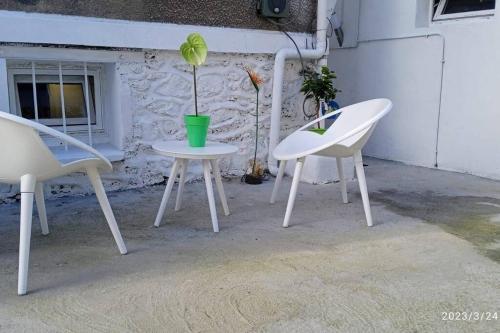two white chairs and a table with a potted plant on it at Superbe et vaste Logement(F) avec WIFI Gratuit in Drancy
