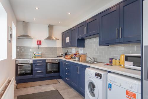 a kitchen with blue cabinets and a washer and dryer at The Avenue Belfast in Belfast