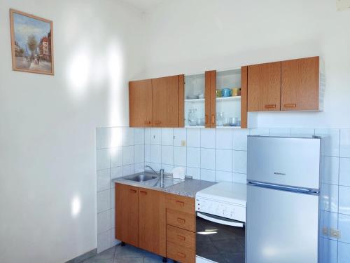 uma cozinha com armários de madeira e um frigorífico branco em Studio Apartment em Rogoznica
