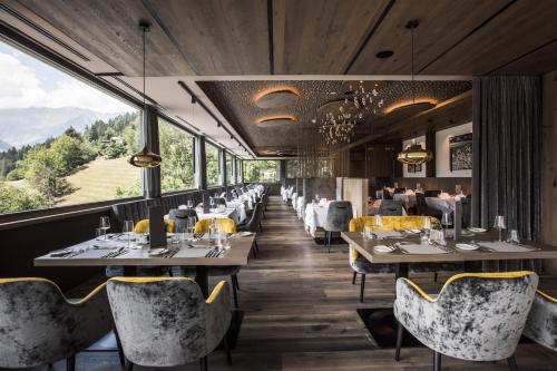 サン・レオナルド・イン・パッシーリアにあるHotel Bad Fallenbachの山を背景にテーブルと椅子が備わるレストラン