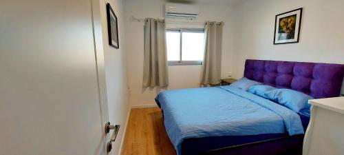 a bedroom with a purple bed and a window at Eilat Octopus Apartment - אילת אוקטופוס -שני חדרים וסלון, בריכה בקיץ in Eilat