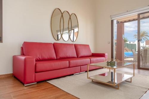 un sofá rojo en una sala de estar con mesa en Villa Rubi 19 Golf Private Pool Caleta de Fuste By Holidays Home, en Caleta de Fuste