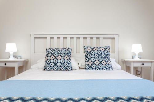 a bed with blue and white pillows on it at Villa Rubi 19 Golf Private Pool Caleta de Fuste By Holidays Home in Caleta De Fuste