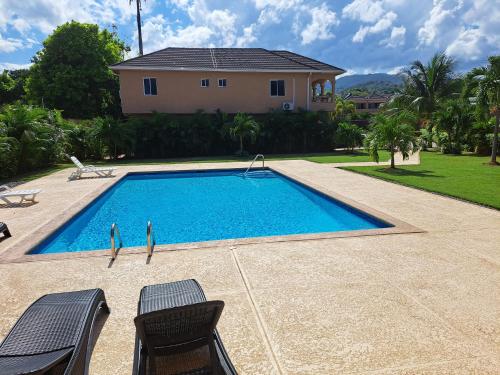 a swimming pool with two chairs and a house at palmview estate townhouse in Mammee Bay