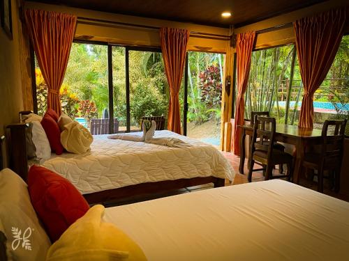 um quarto com 2 camas, uma mesa e cadeiras em Hotel Heliconias Nature Inn & Hot Springs em La Fortuna