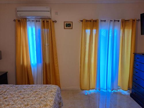 a bedroom with yellow and blue curtains and a bed at palmview estate townhouse in Mammee Bay