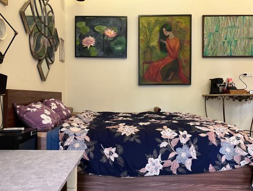 um quarto com uma cama e três pinturas na parede em The First Ba Trieu Ha Noi em Hanói