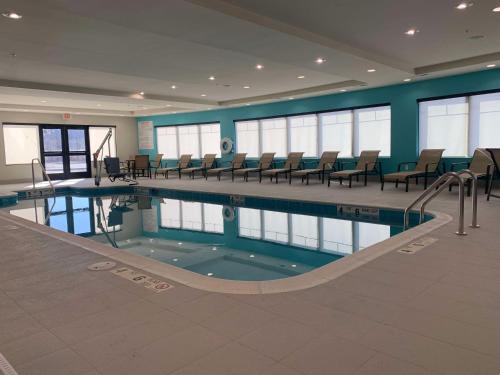 a swimming pool in a building with chairs around it at Best Western Plus Horseheads Inn & Suites in Horseheads