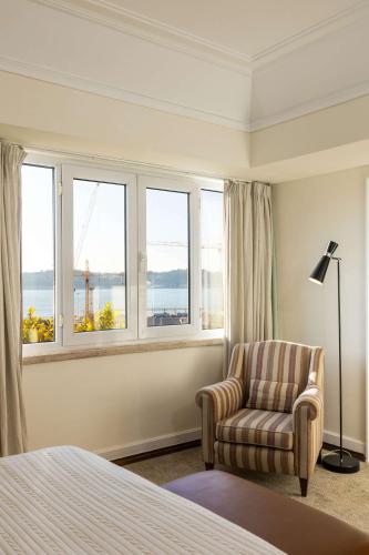 a bedroom with a chair and windows with a view at As Janelas Verdes Inn - Lisbon Heritage Collection - Riverside in Lisbon