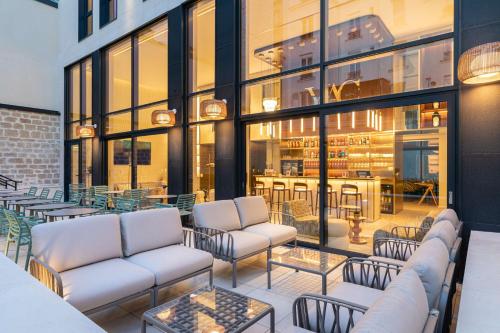 d'une terrasse avec des canapés, des tables et des fenêtres. dans l'établissement Hotel Yac Paris Clichy, a member of Radisson Individuals, à Clichy