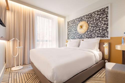 a bedroom with a large white bed and a window at Hotel Yac Paris Clichy, a member of Radisson Individuals in Clichy