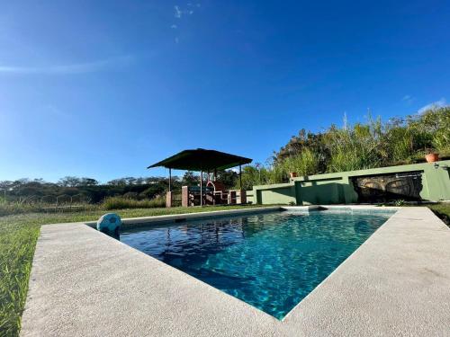 a swimming pool with a table and an umbrella at Airb nb private rooms close to the airport Juan Santa María in Alajuela City