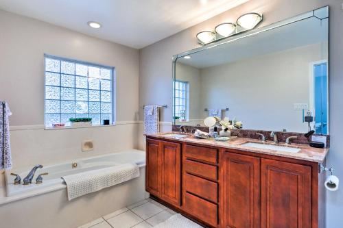 a bathroom with a tub and a sink and a mirror at Ocean Springs Home with Fire Pit and Game Room! in Biloxi
