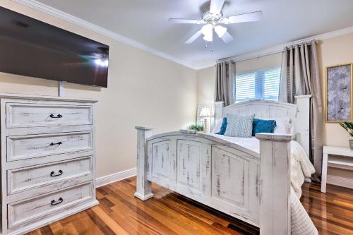a bedroom with a white bed with dressers and a ceiling fan at Ocean Springs Home with Fire Pit and Game Room! in Biloxi